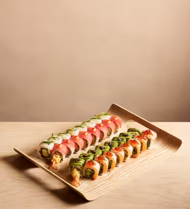 Two neatly arranged sushi rolls on a wooden tray, with colorful toppings like shrimp, avocado, tuna, and green topping. The background is a neutral beige, creating an elegant presentation.
